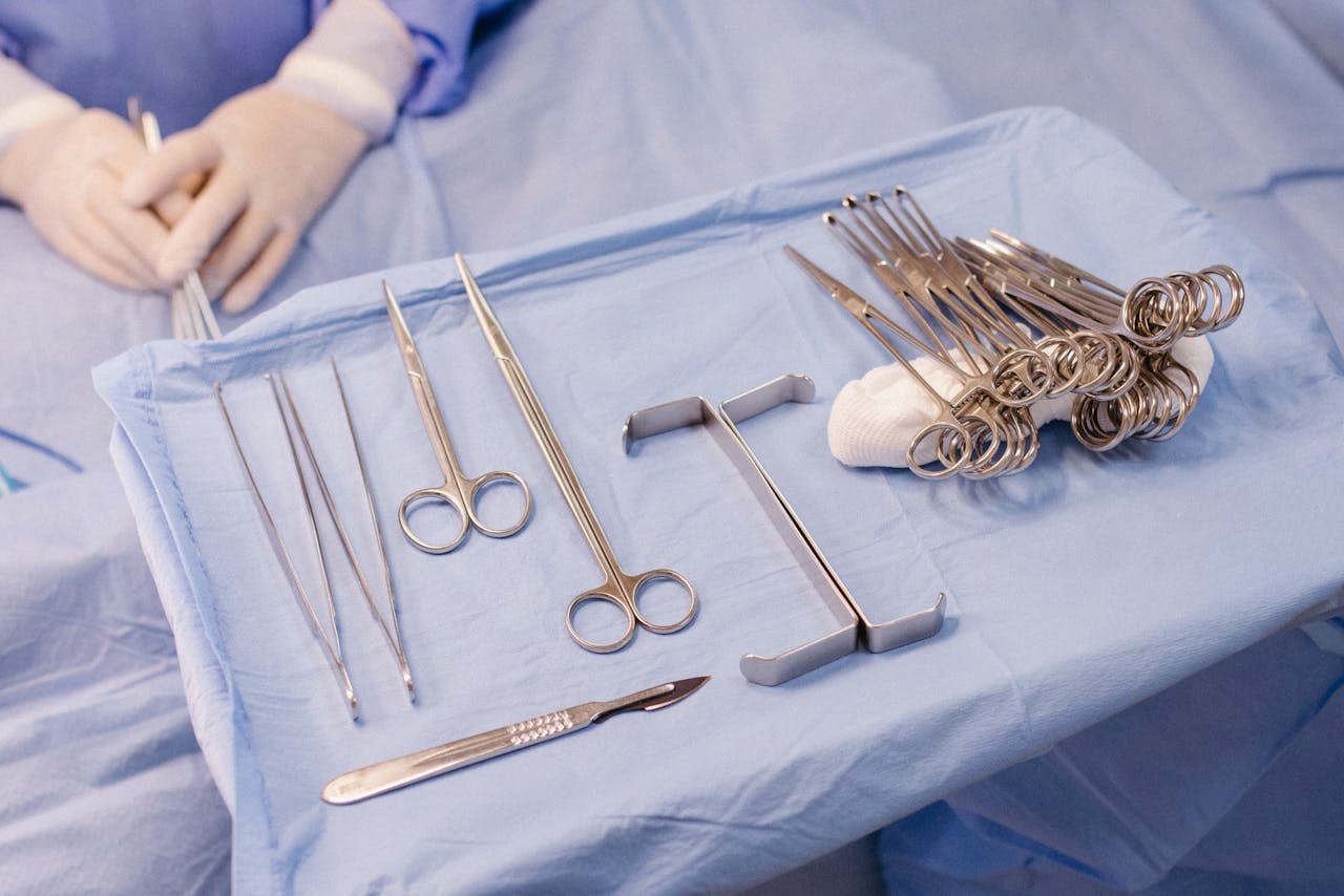 about-01 A set of surgical instruments carefully arranged on a blue drape during an operation.
